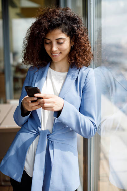 istock Young smiling businesswoman using smart phone in office 1304391829