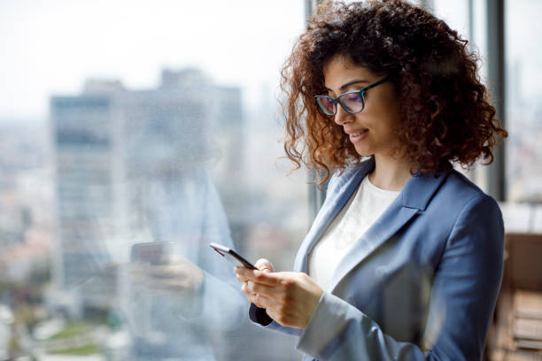 junge geschäftsfrau mit smartphone im büro - business mobile phone telephone women stock-fotos und bilder