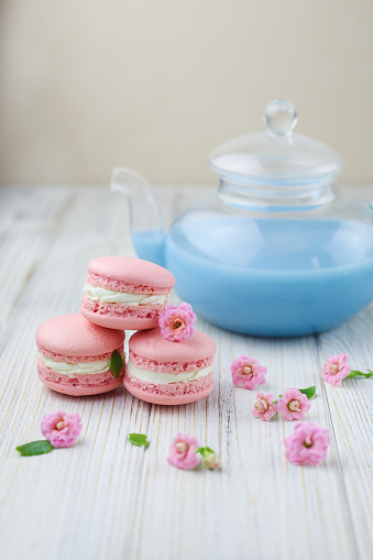 Pink macaroons with the glass pot of blue masala tea. High quality photo