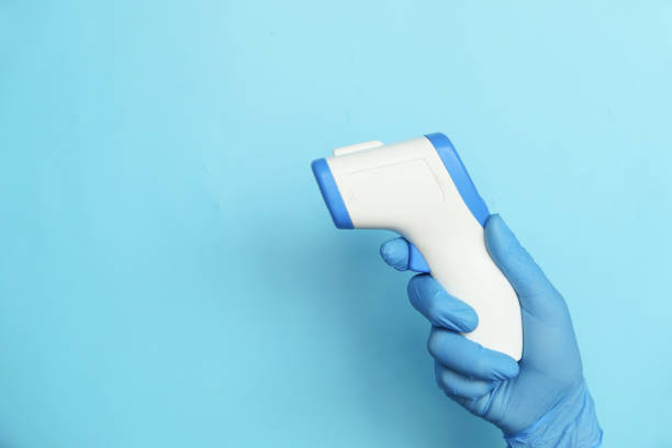 istock Hand holding infrared thermometer to measuring temperature on blue background 1304393065
