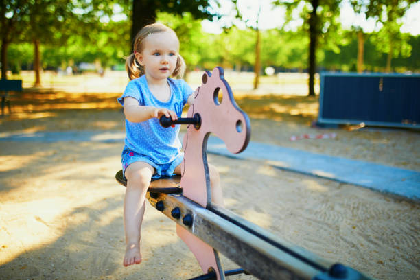 Adorable little girl having fun on seesaw. Toddler playing on playground. Outdoor activities for kids