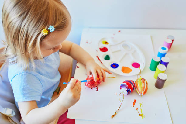 istock Adorable little girl painting eggs for Easter 1304393762