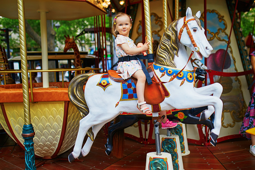 Adorable little girl on the playground. Toddler having fun on vintage French merry-go-round in Paris. Outdoor activities for small kids