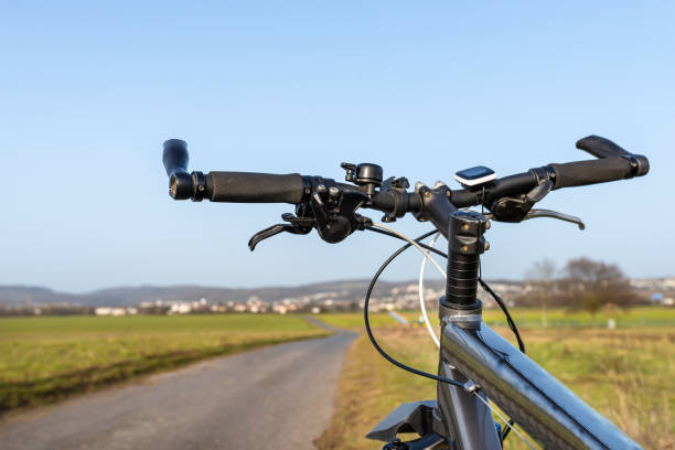 istock Mountain bike handlebar seen from the first person perspective. Visible bicycle frame and bicycle accessories on the handlebar, and the road in the background. 1304394215