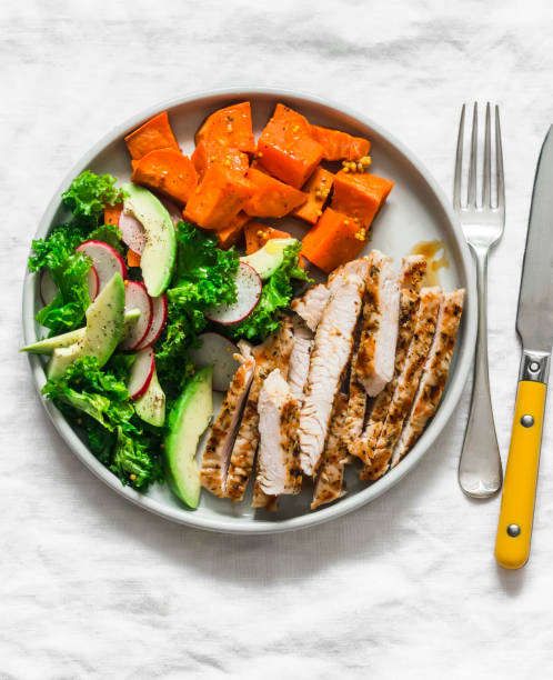 istock Balanced diet lunch - grilled turkey, boiled sweet potatoes, kale cabbage, avocado, cucumbers, radish salad on a light background, top view 1304394611