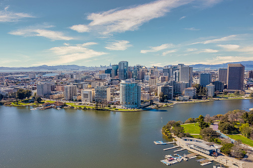 An aerial view on a sunny day of Lake Merritt in Oakland. Oakland skyline with the San Francisco skyline behind it.