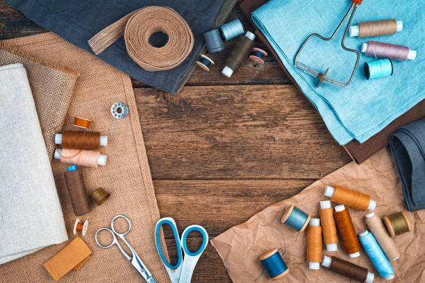 istock Fabrics, threads and scissors with a ribbon on a natural wooden background 1304397982