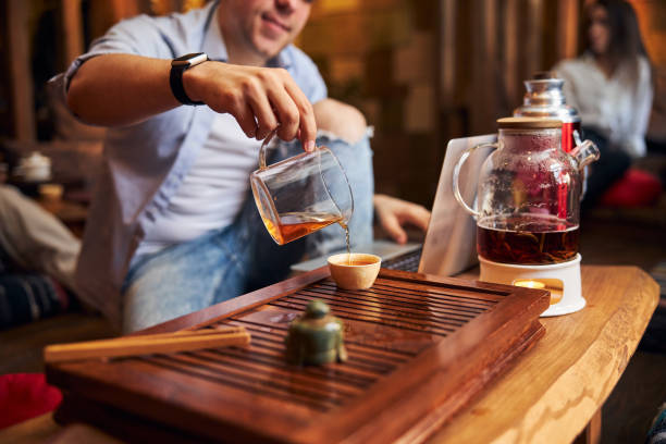 istock Young man drinking tea and using laptop in cozy cafe 1304398428