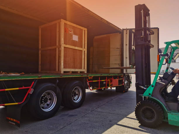 istock Worker driving forklift loading shipment carton boxes goods on wooden pallet at loading dock from container truck to warehouse cargo storage in freight logistics, transportation industrial, delivery 1304399879