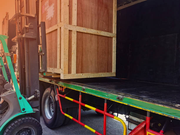 istock Worker driving forklift loading shipment carton boxes goods on wooden pallet at loading dock from container truck to warehouse cargo storage in freight logistics, transportation industrial, delivery 1304399881