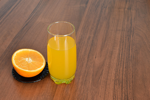 Healthy lifestyle. There is a glass of freshly squeezed juice and an orange on the kitchen table.