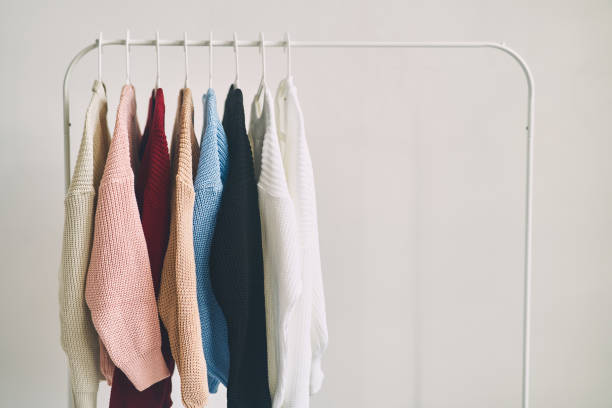 suéteres de lana de mujer multicolores en perchas. venta en una tienda de moda - barra para colgar la ropa fotografías e imágenes de stock