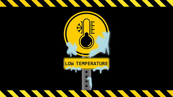 Low temperature sign on a black background with yellow black stripes. Yellow black banner. Yellow warning sign. Yellow low temperature placard. Ice on the placard. Yellow black thermometer and snow flake symbol. Electricity, power outage, short circuit, high voltage, danger, low temperature, freezing cold concepts.