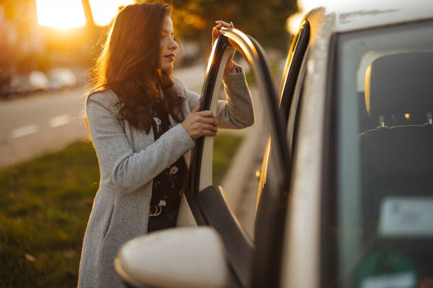 istock Young woman getting into car in town 1304401352