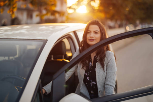 istock Young woman getting into car in town 1304401370