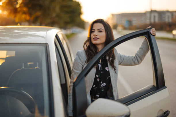 istock Young woman getting into car in town 1304401389