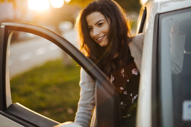 istock Young woman getting into car in town 1304402510