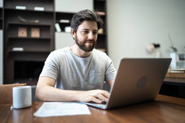 istock Mid adult man using laptop working from home 1304404057