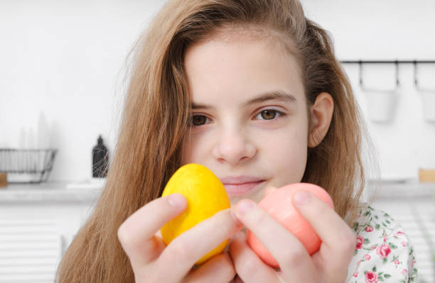 ragazza europea 10 anni con uova di pasqua rosa e gialle in mano da vicino - 10 11 years cheerful happiness fun foto e immagini stock