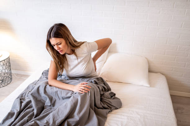 woman in bed having backache. - dor de costas imagens e fotografias de stock