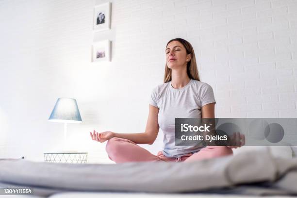 Woman Meditating In The Bedroom Stock Photo - Download Image Now - Routine, Morning, Bed - Furniture