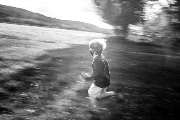 istock 8 year old boy running on meadow, Protective mask, Black and white 1304411687