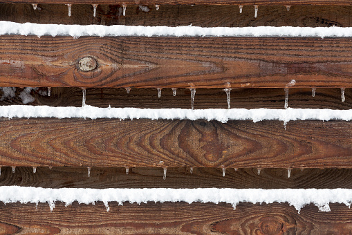 Snow and icicles on wooden fence. As textured background