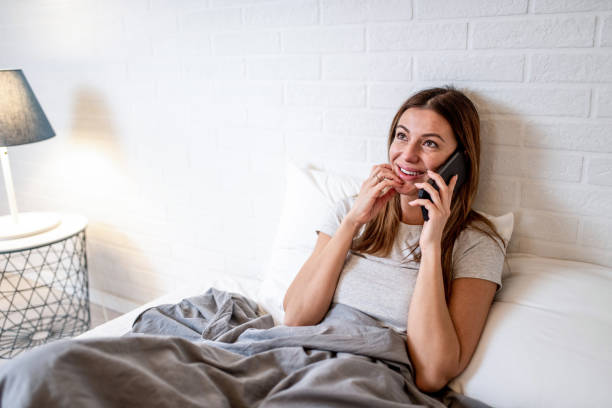 istock Young woman talking on phone while relaxing in bed. 1304420239