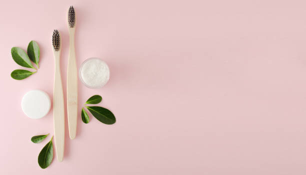 istock Eco-friendly bamboo toothbrushes, dentifrice and green leaf on pink background. 1304420413