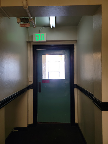 On the fifth floor of an apartment building, the fire exit stairs are blocked by this door with a window in it.