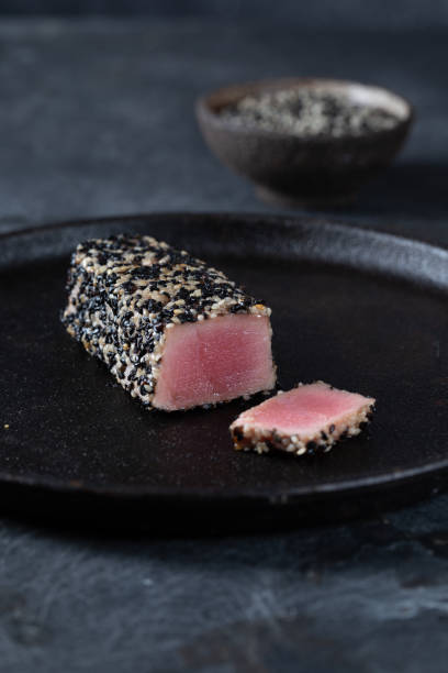 istock Fried tuna steak in black sesame with asparagus on black plate 1304423657