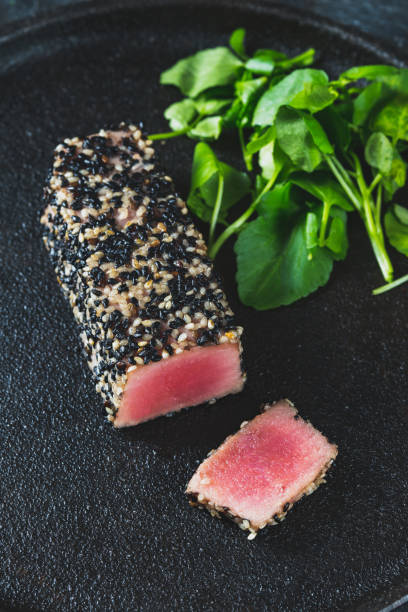 istock Fried tuna steak in black sesame with asparagus on black plate 1304423667