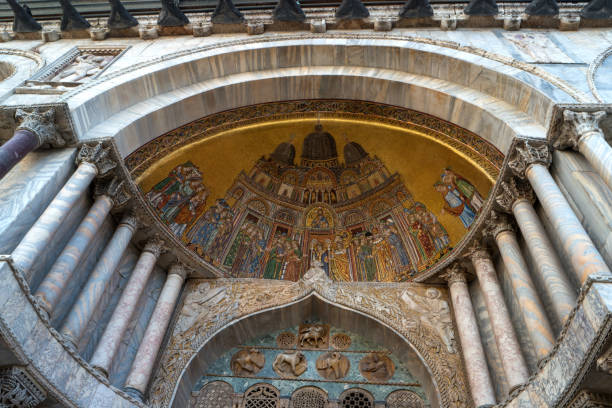 Venice, Italy - February 12, 2024: Golden mosaics depicting biblical scenes and latin inscriptions adorn the ceiling of St. Mark's Basilica in Venice, Italy, showcasing the rich history and artistry of this iconic landmark