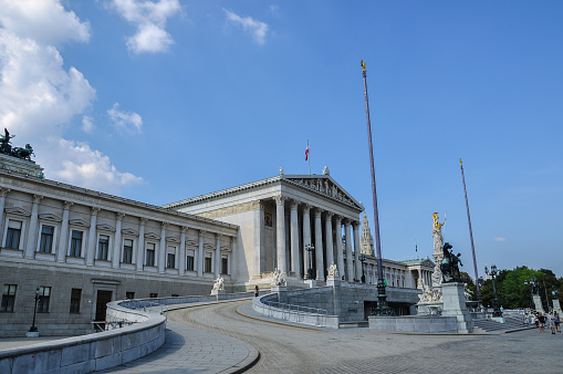Vienna, Austria - 10.09.2016: Panorama of the Austrian Parliament Building. The building was built in 1874-1883 in the neo-Greek style by design of architect Theophil Hansen. The Athena Fountain in front of the building was designed by Theophil Hansen in 1870 and created in 1898-1902 by various sculptors. The building of Vienna Town Hall is visible on the right edge of the image.