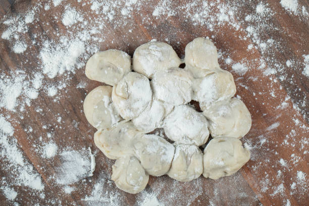 istock A wooden round board with uncooked dumplings and flour 1304428434