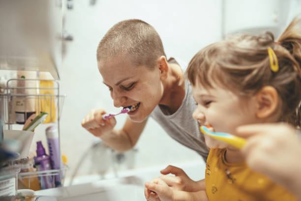 Cancer patient mother brushing teeth with her daughter