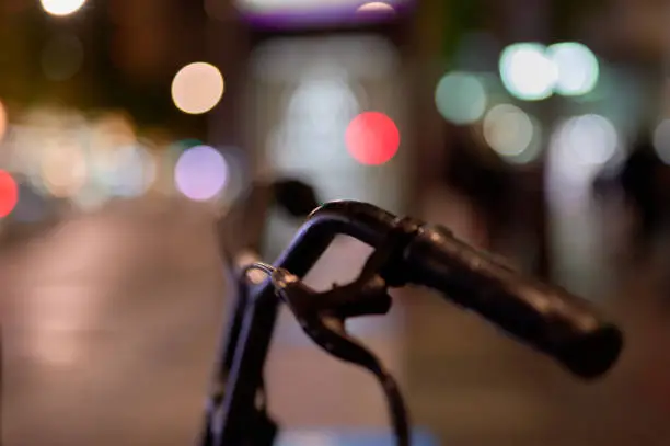 Photo of handlebars of a rental bike on a city avenue at night