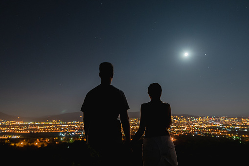 silhouette of a girl with a view of the city with a full moon