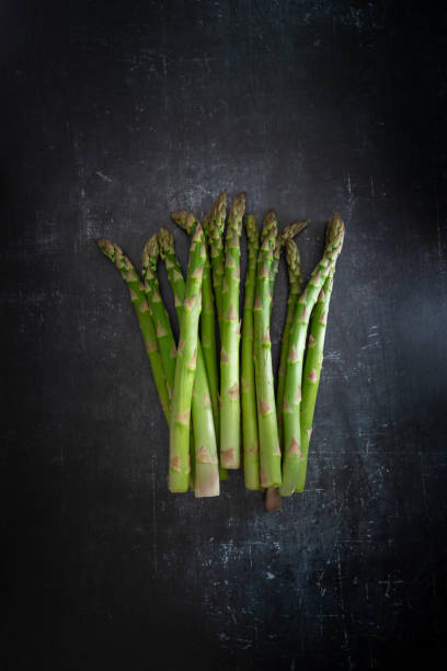 istock A bundle of fresh green asparagus on a textured black background, copy space, vertical 1304432928