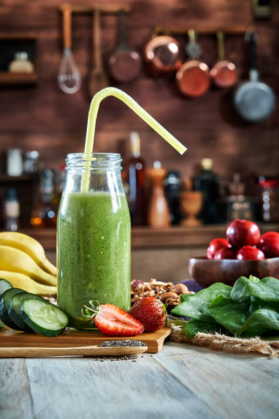 nourriture saine : smoothie vert de désintoxication dans la bouteille sur une table rustique. - green smoothie vegetable juice fruit photos et images de collection