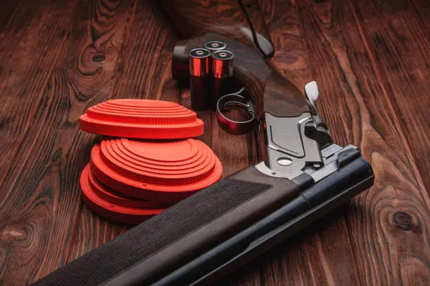 Photo of Clay target plates for shooting with rifle on wooden background.