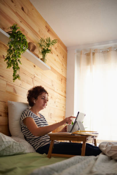 istock Woman telecommuting from her bed while holding a cup of coffee. 1304445213