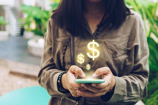 Mujer utilizar gadget teléfono inteligente móvil ganar dinero en línea con el icono de dólar emergente. Tecnología fintech empresarial en concepto de smartphone. photo
