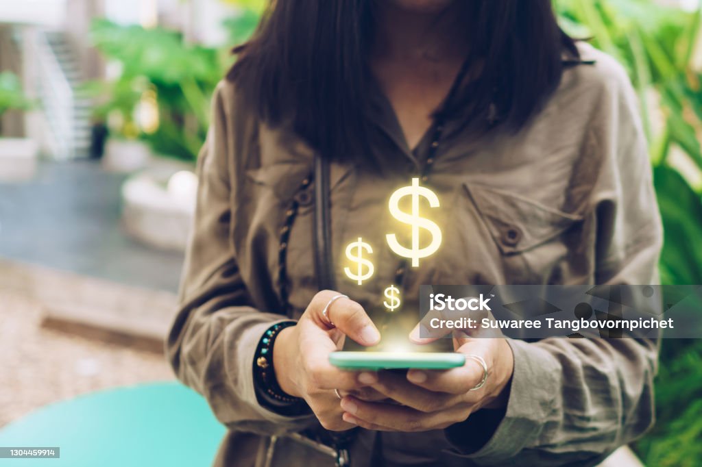 Woman use gadget mobile smartphone earn money online with dollar icon pop up. Business fintech technology on smartphone concept. Paper Currency Stock Photo