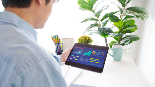 istock Young asian man holding digital tablet with business chart on screen while working at home, people and technology, online learning, education, lifestyle concept 1304460880