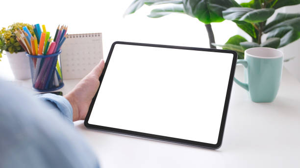 istock Close up of man hand holding digital tablet with blank screen on working table background for mock up, template 1304461497