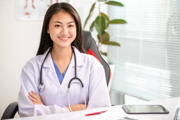 Young woman doctor smiling at office stock photo
