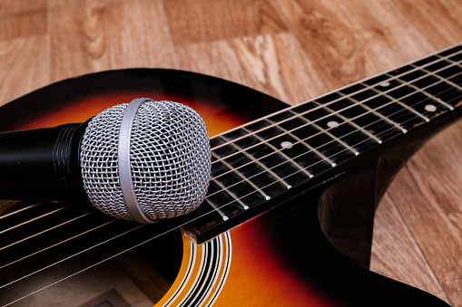 Microphone and guitar on a wooden background, copy space