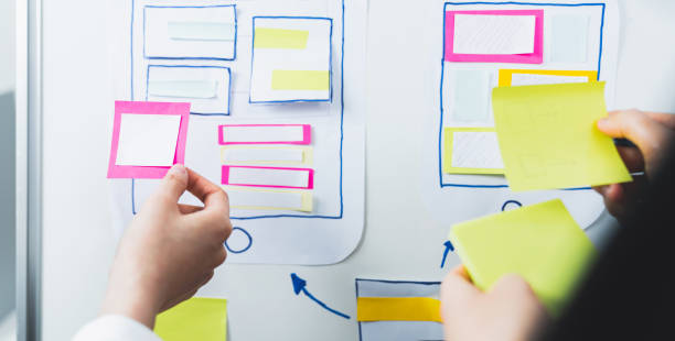 istock Mobile Application Designers are development on smartphone and pink paper note on hand, creative sketch planning. 1304474820
