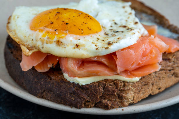 istock Fresh salmon, egg sandwich, close up. Salted salmon, fried egg, butter and dark bread 1304475911